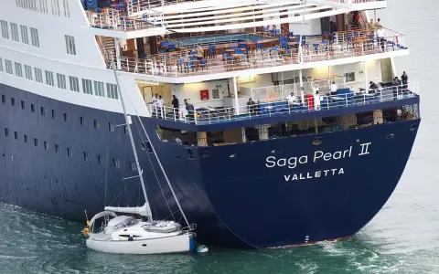 Una piccola barca a vela si trova in una **posa a tolda di nave irregolare** accanto alla massiccia nave da crociera "Saga Pearl II".
