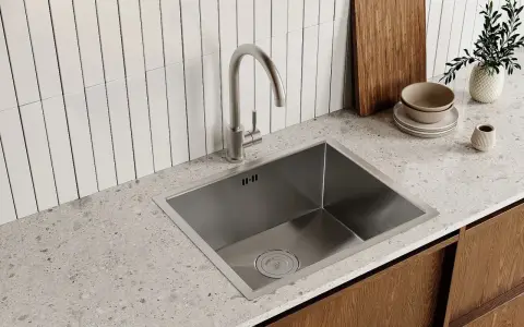 Rubinetto cucina moderno in acciaio inox, pronto per essere smontato. Sotto, un lavello squadrato e un piano in quarzo.