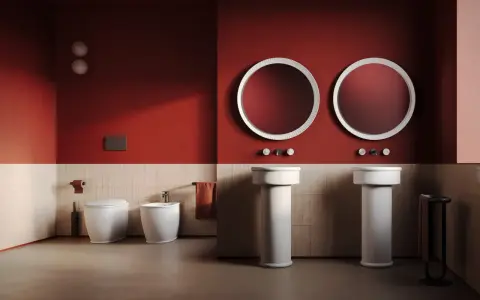 Bagno moderno con wc, bidet e due lavabi a colonna. L'artceramica bianca risalta sulle pareti rosse e le piastrelle chiare.