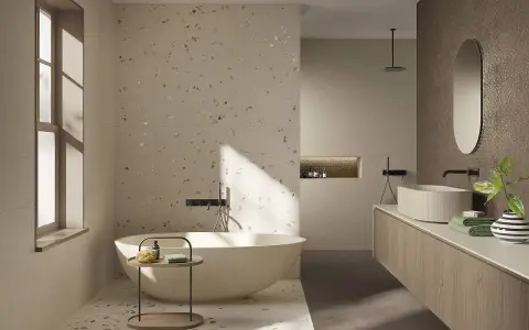 Bagno moderno con vasca freestanding e lavabo su mobile in legno. Il pavimento fap, con le sue venature chiare e inclusioni dorate, riflette la luce naturale.