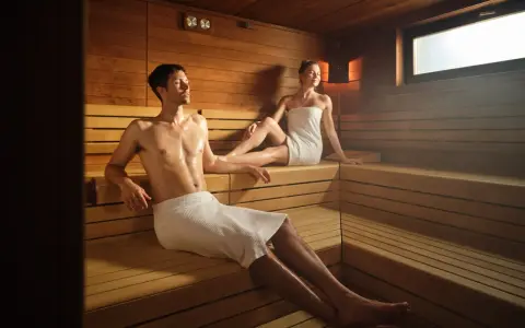 Coppia rilassata in sauna, un ambiente caldo e legnoso. Il calore aiuta a purificare il corpo, e molti credono che fare la sauna fa dimagrire.
