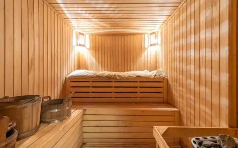 Interno di una sauna norvegese in legno, con panche, secchi e luci soffuse.