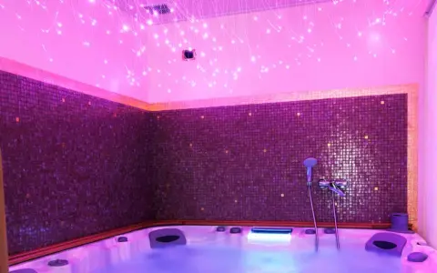 Jacuzzi con luci soffuse e mosaici viola, un'oasi di relax per la cromoterapia spa.