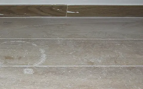 Stucco bianco residuo su piastrelle effetto legno. Ecco come togliere lo stucco dalle piastrelle per un risultato impeccabile.
