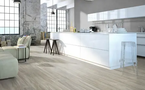 Cucina moderna con isola bianca, divano e pavimenti in legno chiaro. Quanti pavimenti si possono sovrapporre per creare questo look?