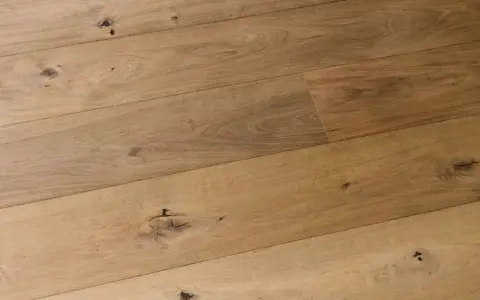 Dettaglio di assi di parquet prefinito in legno chiaro con nodi evidenti. Lo spessore del legno conferisce robustezza.