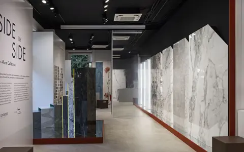 Interno showroom con lastre di marmo e design, esposizione "Side by Side" di Cotto d'Este, rivenditori di eccellenza.