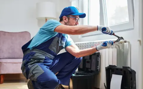 Tecnico con attrezzi lavora su termosifone. Scopri il lavaggio termosifoni in ghisa costo per un riscaldamento efficiente.