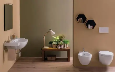 Bagno moderno con lavabo sospeso, bidet e vaso **ceramica globo**. Tavolino con piante e lampada.