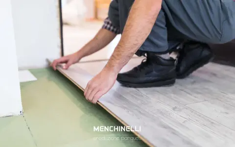 Installazione di un parquet flottante con finitura effetto legno chiaro. Un artigiano posa le tavole con cura.
