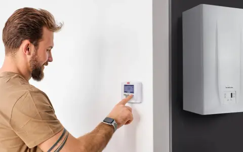 Uomo interagisce con termostato digitale, mostrando la differenza tra termostato e cronotermostato per ottimizzare il riscaldamento.