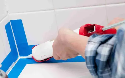 Applicazione sigillante per una doccia senza piatto, impermeabilizzazione perfetta con nastro blu.
