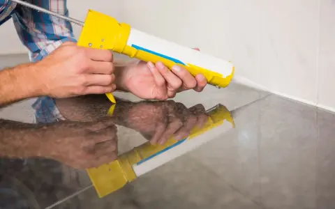 Applicazione di silicone con pistola per sigillare il box doccia.