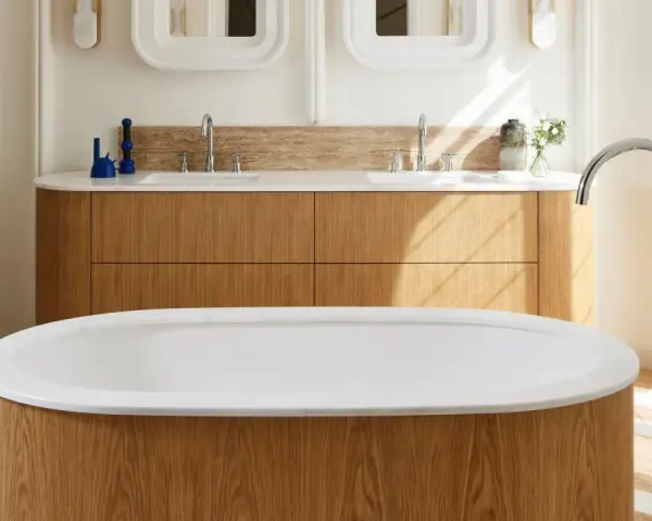 Una vasca da bagno di lusso con finiture in legno e marmo, rubinetteria cromata e un mobile doppio lavabo in legno.