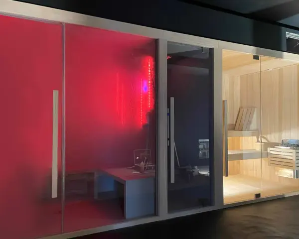 Tre cabine per un'esperienza spa in casa: una rossa con luci LED, una scura e una in legno con sauna tradizionale.