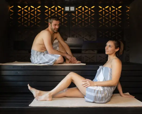 Coppia rilassata in un bagno turco, con clessidra per misurare il bagno turco quanto tempo.
