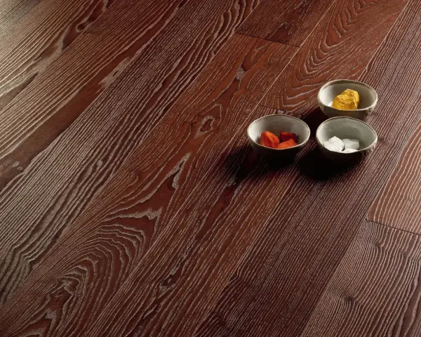 Superficie in parquet massello o prefinito con venature marcate. Tre ciotoline con elementi decorativi colorati.