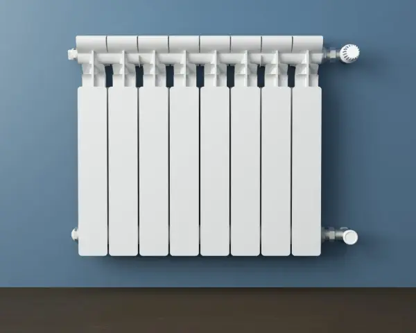 Un termosifone bianco su muro blu. Si intravedono i tubi interni e la valvola termostatica, mostrando come è fatto un termosifone all'interno.