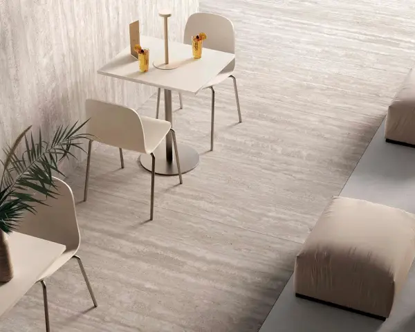 Un'area lounge moderna con tavolini, sedie e pouf su eleganti mattonelle senza fuga effetto pietra.