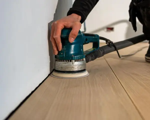 Levigatura del parquet: dopo quanto tempo si può camminare? La levigatrice orbitale lavora sul legno chiaro, pronto per essere calpestato.