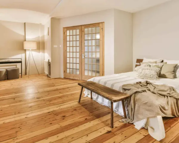 Camera mostra un letto, un armadio e un pavimento in legno. Il parquet è stato pulito con alcool, rendendolo brillante.