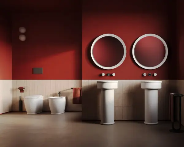 Bagno moderno con wc, bidet e due lavabi a colonna. L'artceramica bianca risalta sulle pareti rosse e le piastrelle chiare.