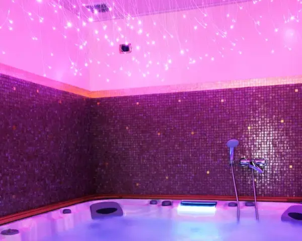 Jacuzzi con luci soffuse e mosaici viola, un'oasi di relax per la cromoterapia spa.