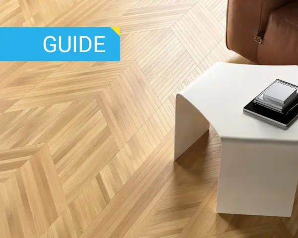 Guida: parquet spazzolato pro e contro. Pavimento in legno con motivo a spina di pesce, tavolino bianco e divano in pelle marrone.