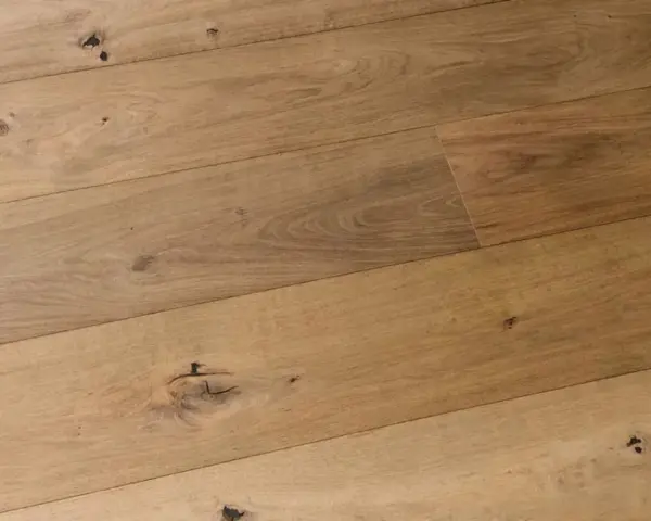 Dettaglio di assi di parquet prefinito in legno chiaro con nodi evidenti. Lo spessore del legno conferisce robustezza.