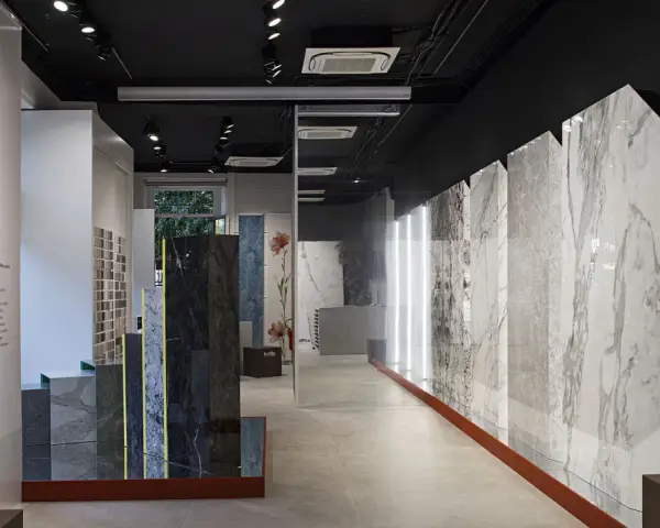 Interno showroom con lastre di marmo e design, esposizione "Side by Side" di Cotto d'Este, rivenditori di eccellenza.