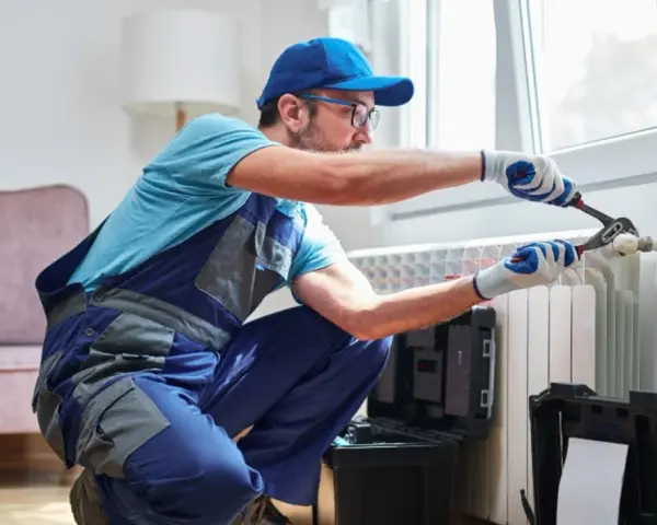 Tecnico con attrezzi lavora su termosifone. Scopri il lavaggio termosifoni in ghisa costo per un riscaldamento efficiente.