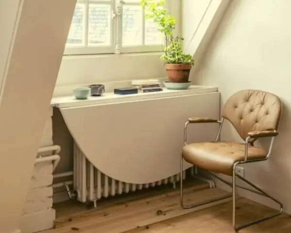 Angolo studio con sedia in pelle e un tavolo ribaltabile che nasconde un termosifone. Ricorda: non coprire i termosifoni per un riscaldamento efficiente.