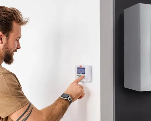 Uomo interagisce con termostato digitale, mostrando la differenza tra termostato e cronotermostato per ottimizzare il riscaldamento.