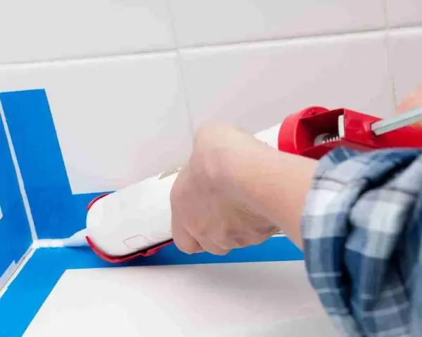 Applicazione sigillante per una doccia senza piatto, impermeabilizzazione perfetta con nastro blu.