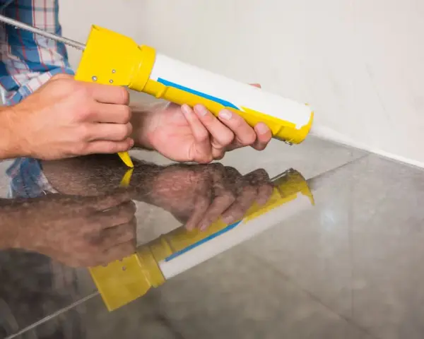 Applicazione di silicone con pistola per sigillare il box doccia.