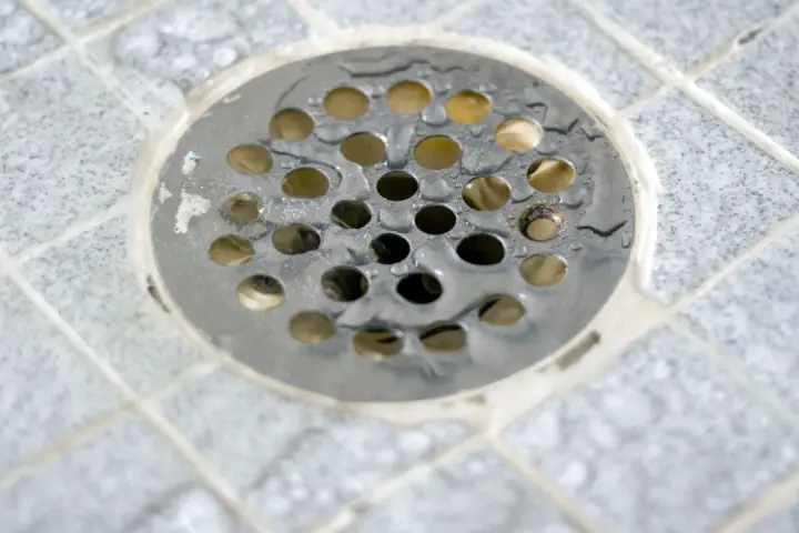 Scarico doccia a pavimento con piastrelle grigie e acqua. La pendenza doccia a pavimento assicura il corretto deflusso.