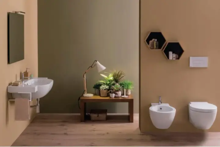 Bagno moderno con lavabo sospeso, bidet e vaso **ceramica globo**. Tavolino con piante e lampada.