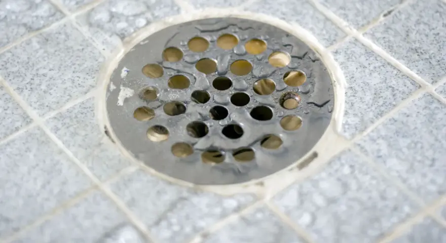Scarico doccia a pavimento con piastrelle grigie e acqua. La pendenza doccia a pavimento assicura il corretto deflusso.