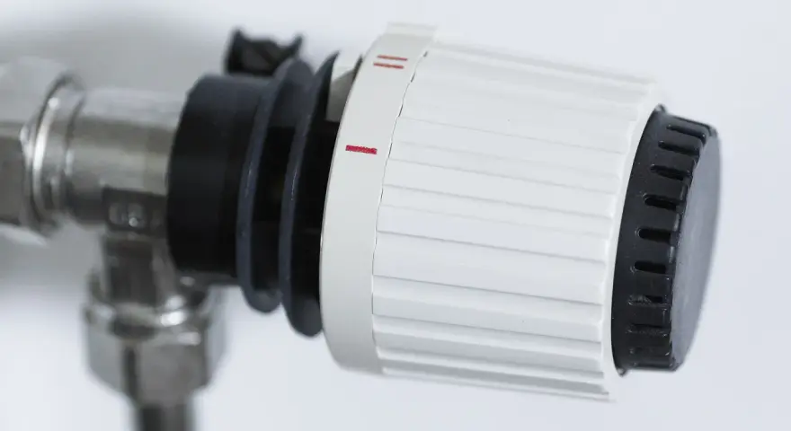 Dettaglio di un detentore termosifone con ghiera bianca e nera, impostato su una tacca intermedia, indica la regolazione della temperatura.