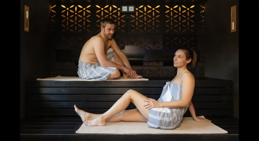 Coppia rilassata in un bagno turco, con clessidra per misurare il bagno turco quanto tempo.