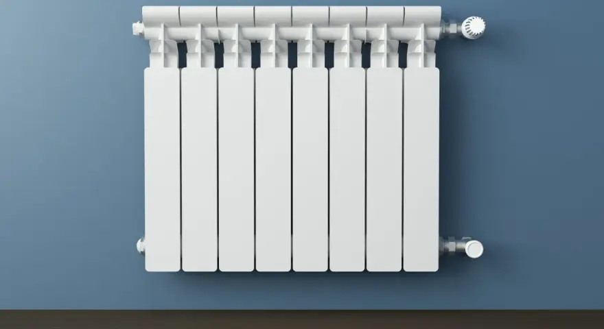 Un termosifone bianco su muro blu. Si intravedono i tubi interni e la valvola termostatica, mostrando come è fatto un termosifone all'interno.