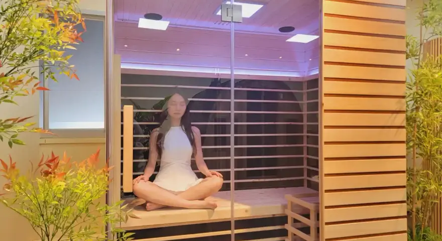 Donna in meditazione in una sauna a infrarossi, un luogo di pace dove ci si chiede perché non sudo in sauna.