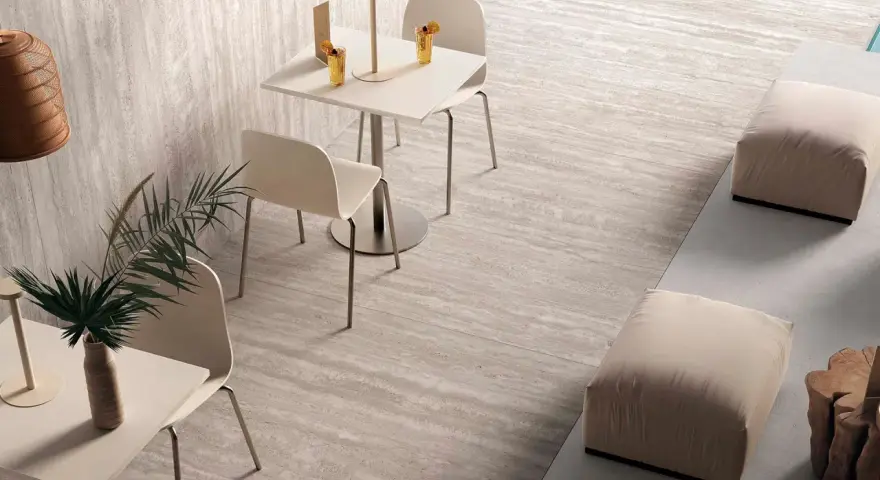 Un'area lounge moderna con tavolini, sedie e pouf su eleganti mattonelle senza fuga effetto pietra.