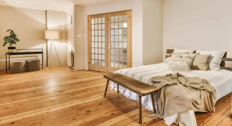 Camera mostra un letto, un armadio e un pavimento in legno. Il parquet è stato pulito con alcool, rendendolo brillante.