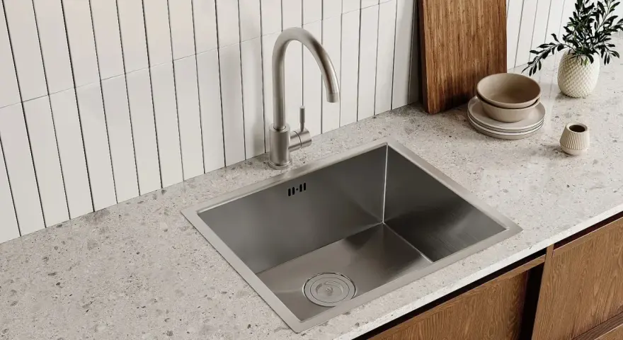 Rubinetto cucina moderno in acciaio inox, pronto per essere smontato. Sotto, un lavello squadrato e un piano in quarzo.