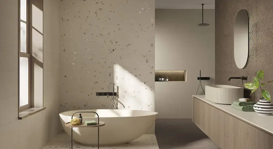 Bagno moderno con vasca freestanding e lavabo su mobile in legno. Il pavimento fap, con le sue venature chiare e inclusioni dorate, riflette la luce naturale.