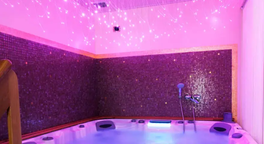 Jacuzzi con luci soffuse e mosaici viola, un'oasi di relax per la cromoterapia spa.
