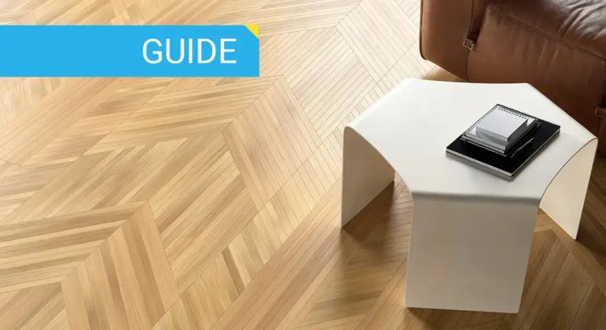 Guida: parquet spazzolato pro e contro. Pavimento in legno con motivo a spina di pesce, tavolino bianco e divano in pelle marrone.