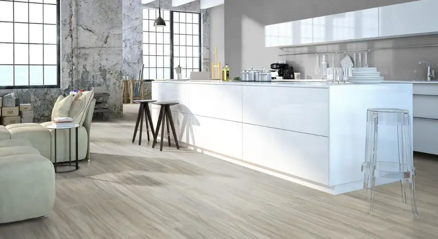 Cucina moderna con isola bianca, divano e pavimenti in legno chiaro. Quanti pavimenti si possono sovrapporre per creare questo look?