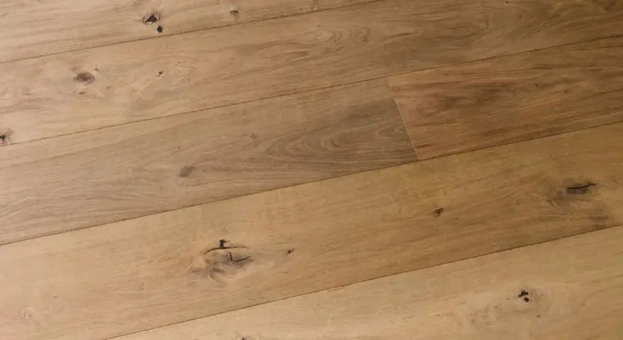 Dettaglio di assi di parquet prefinito in legno chiaro con nodi evidenti. Lo spessore del legno conferisce robustezza.